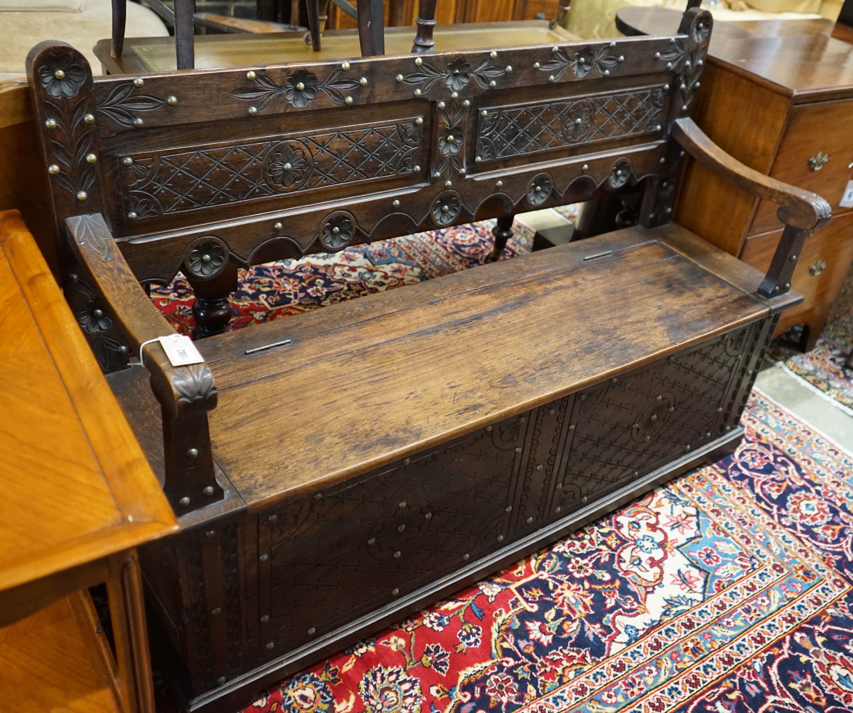 An 18th century style brass studded carved oak box seat settle, length 136cm, depth 40cm, height 93cm